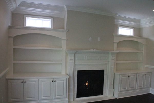 Arched top bookcases with Custom Mantle joining them and cabinets below the counter top.Transom windows placed beneath the crown molding and above the crown on the Bookcases