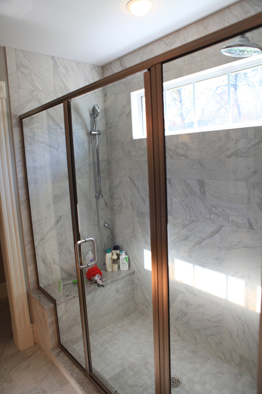 Oversized Master shower with 2 shower heads and a granite seat