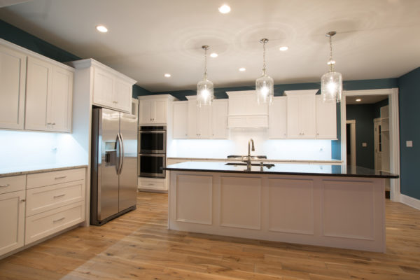 White shaker cabinets with black granite counters.Island has applied molding trim